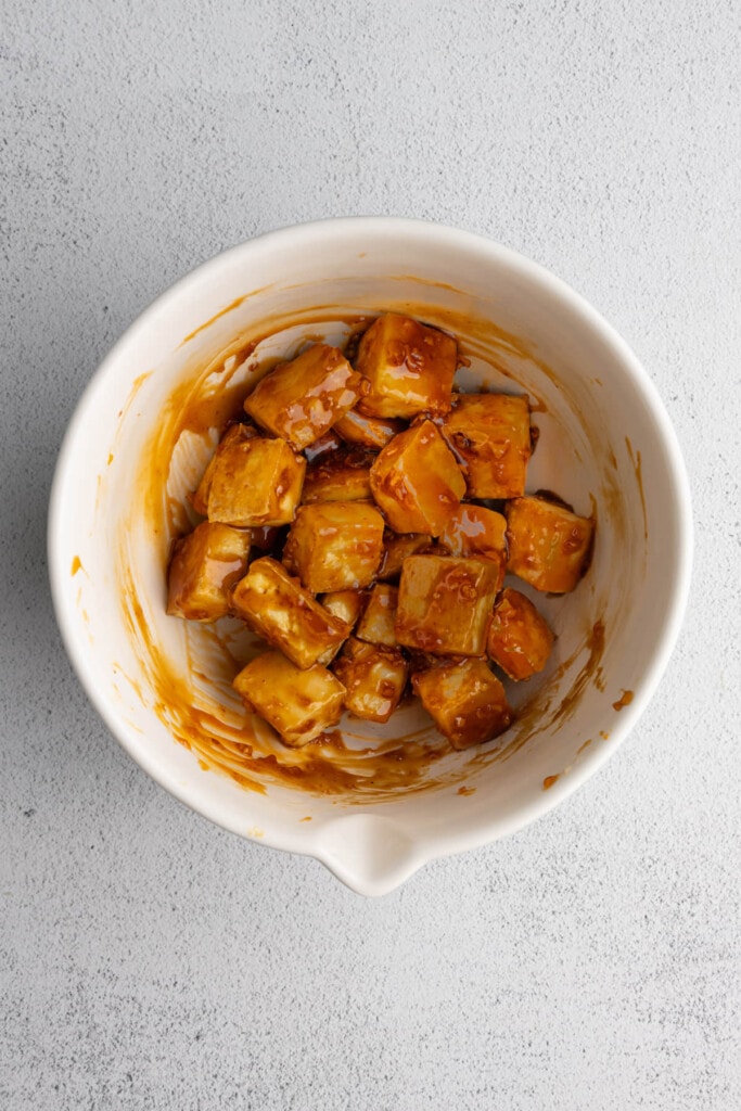 Crispy tofu tossed in honey garlic sauce in a large mixing bowl