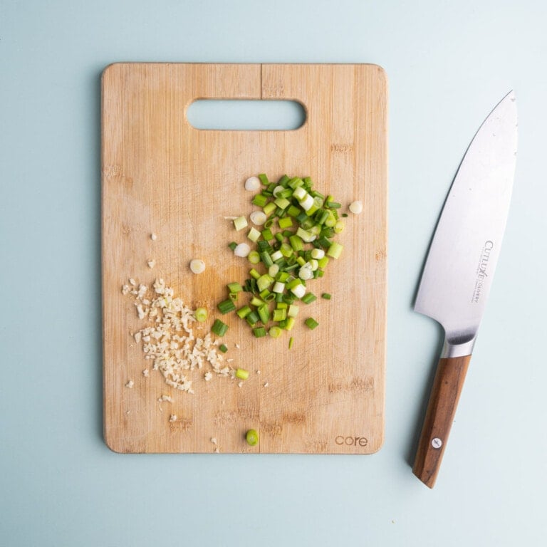 Minced garlic and diced scallions on a cutting board