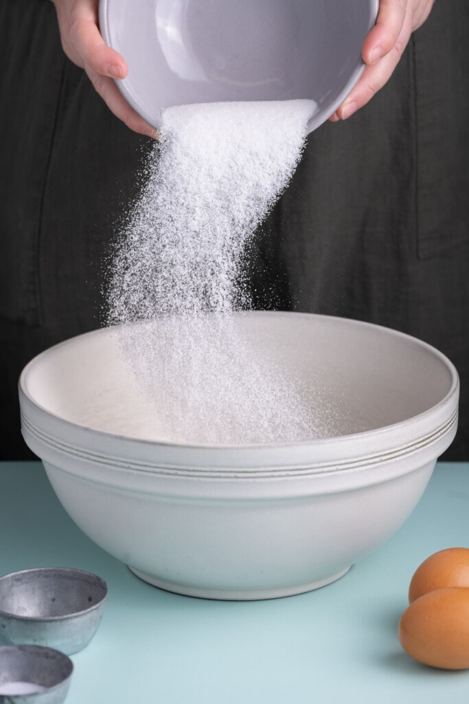 Adding sugar to large mixing bowl with olive oil