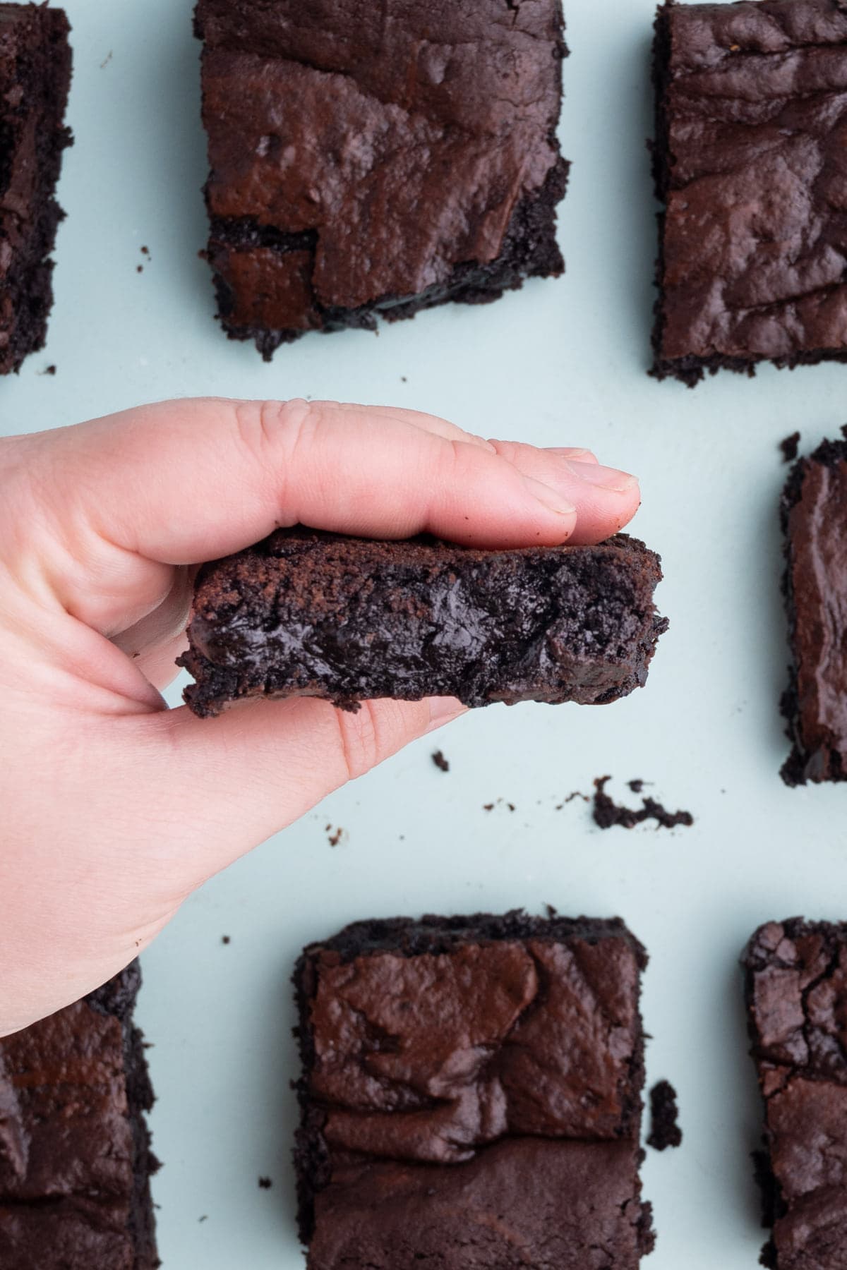 Holding an olive oil brownie in front of the camera to show close up of fudgy inside