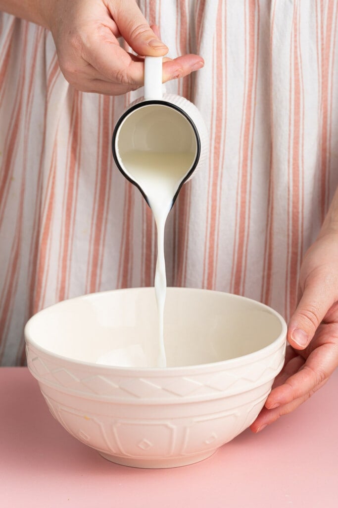 Adding cold milk to a large mixing bowl