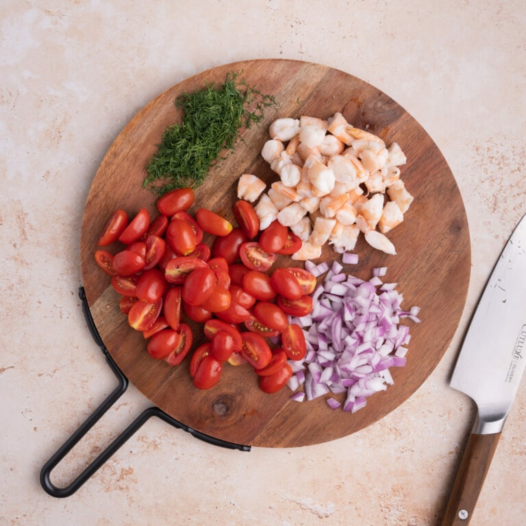 Chopped dill, sliced grape tomatoes, diced red onion, and chopped cooked shrimp prepped and ready for Seafood Pasta Salad