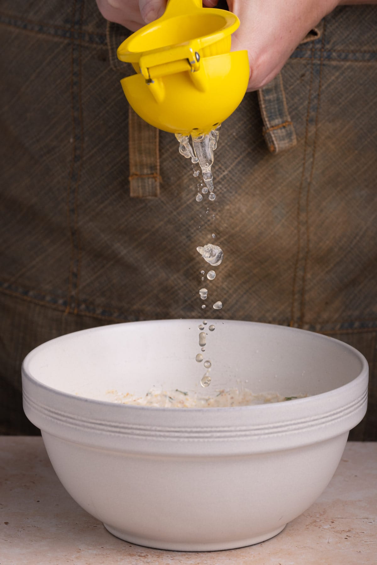 Squeezing fresh lemon juice into creamy sauce for pasta salad