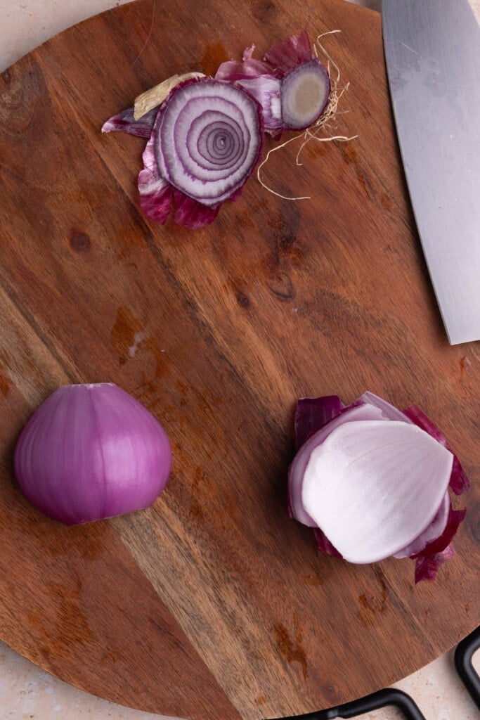 Peeling off outermost layer of red onion to discard