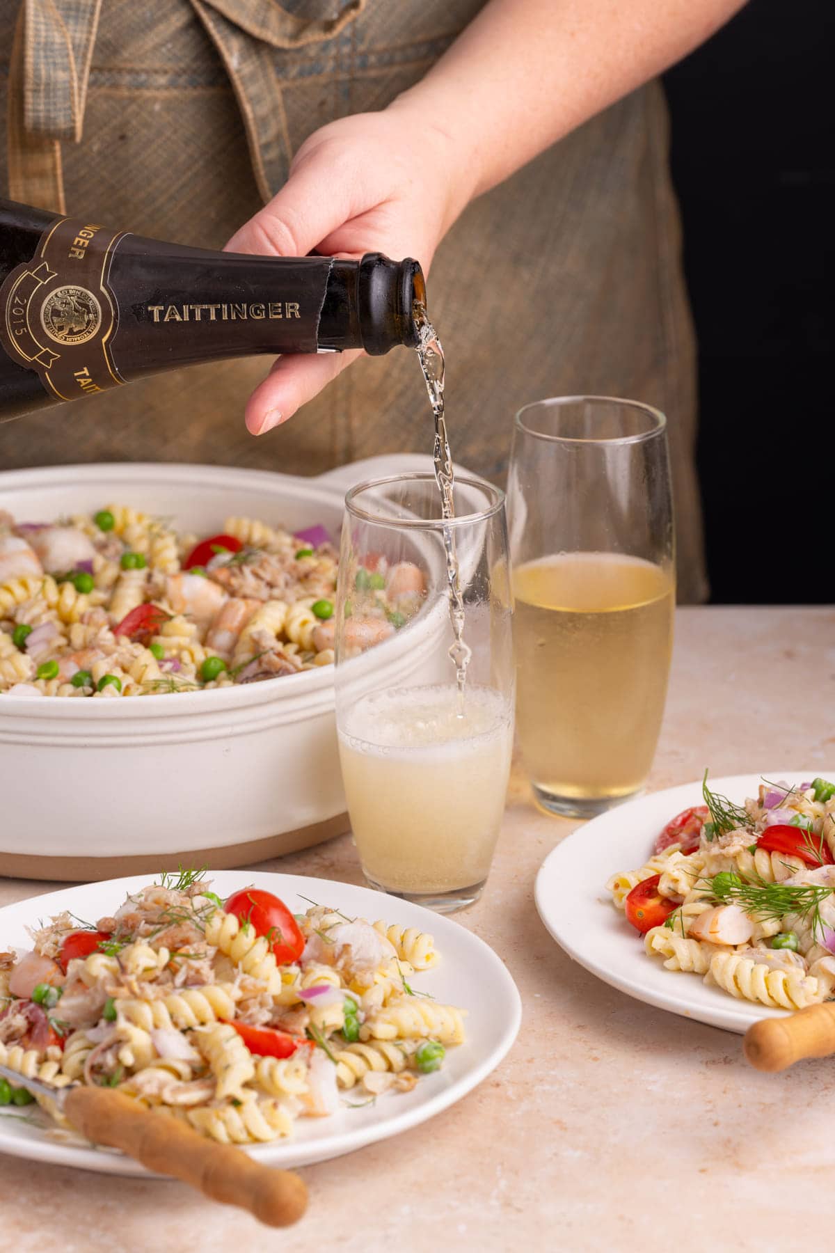 Pouring glass of champagne to serve with Pasta Salad with Seafood