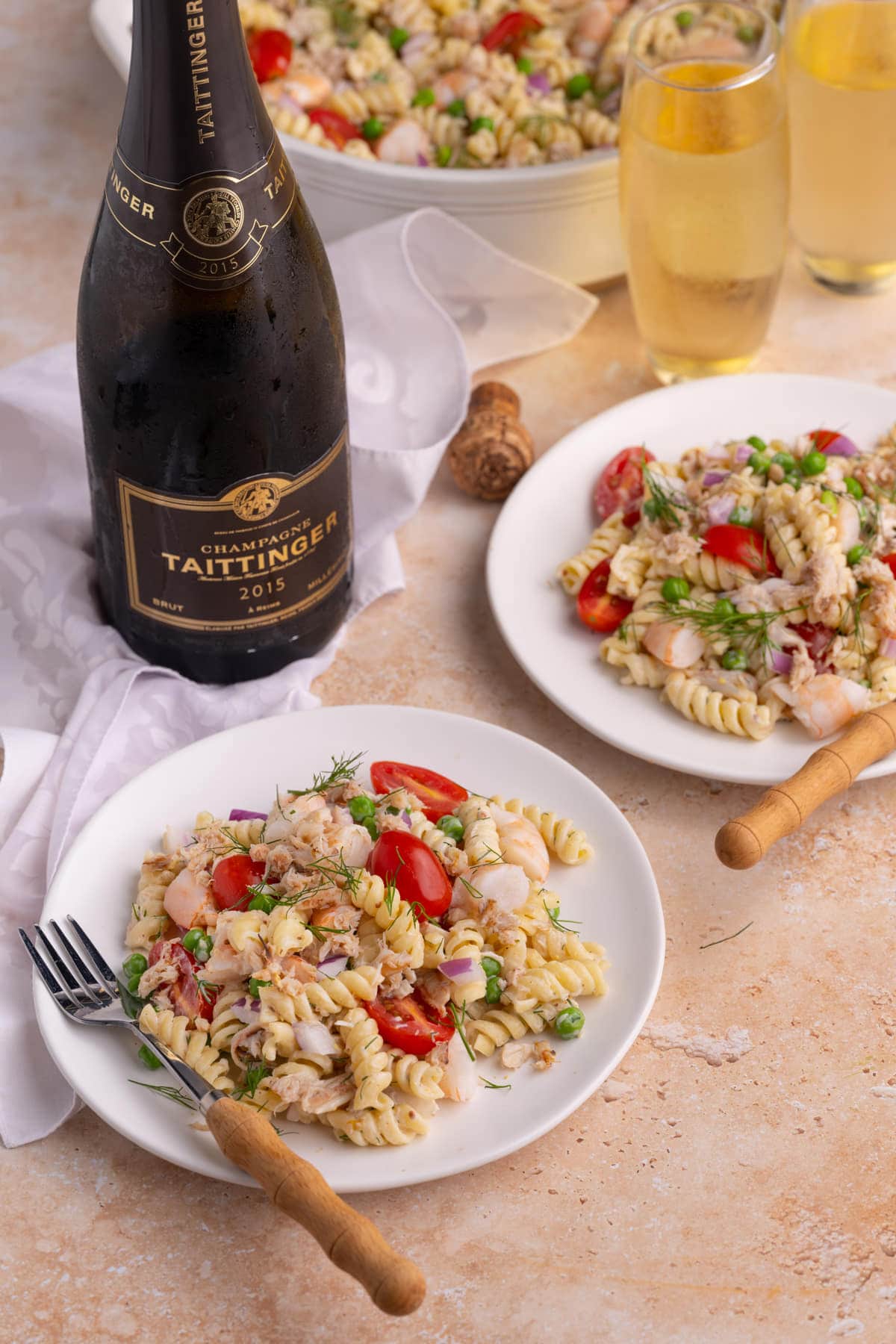 Tablescape with two plates of Seafood Pasta Salad and two glasses of Champagne Taittinger