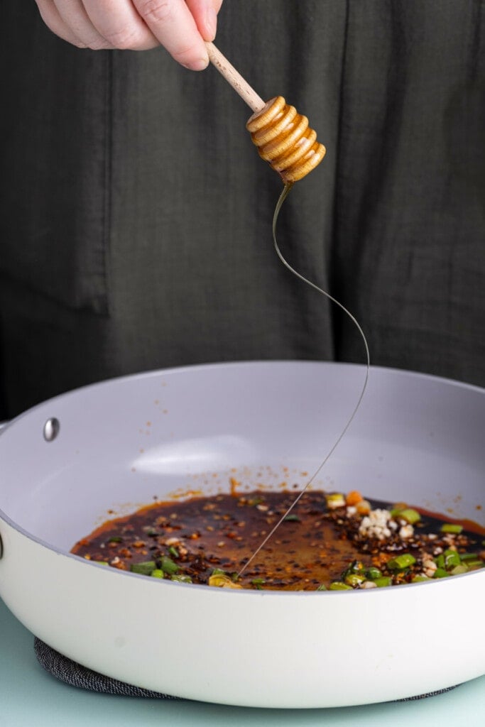 Adding honey to spicy garlic sauce to add sweetness.