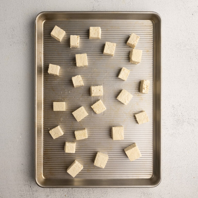 Pressed and cubed tofu with oil and cornstarch on baking sheet