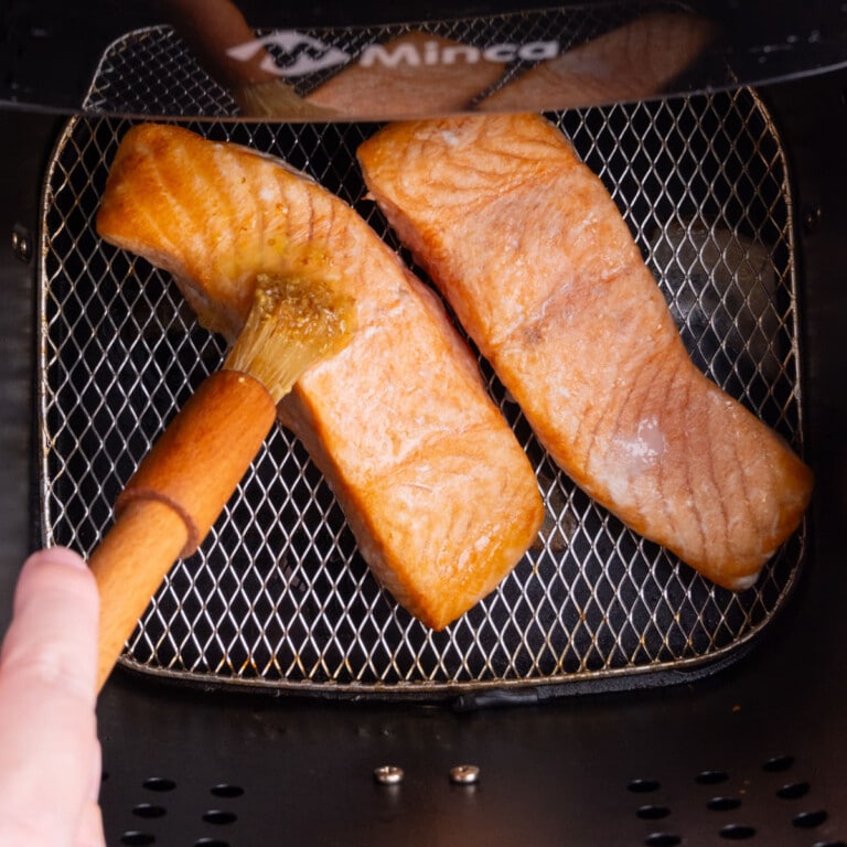 Adding marinade to salmon in air fryer basket