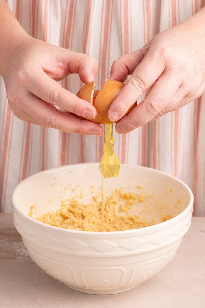 Cracking an egg into pecan caramel chocolate chip cookie dough.
