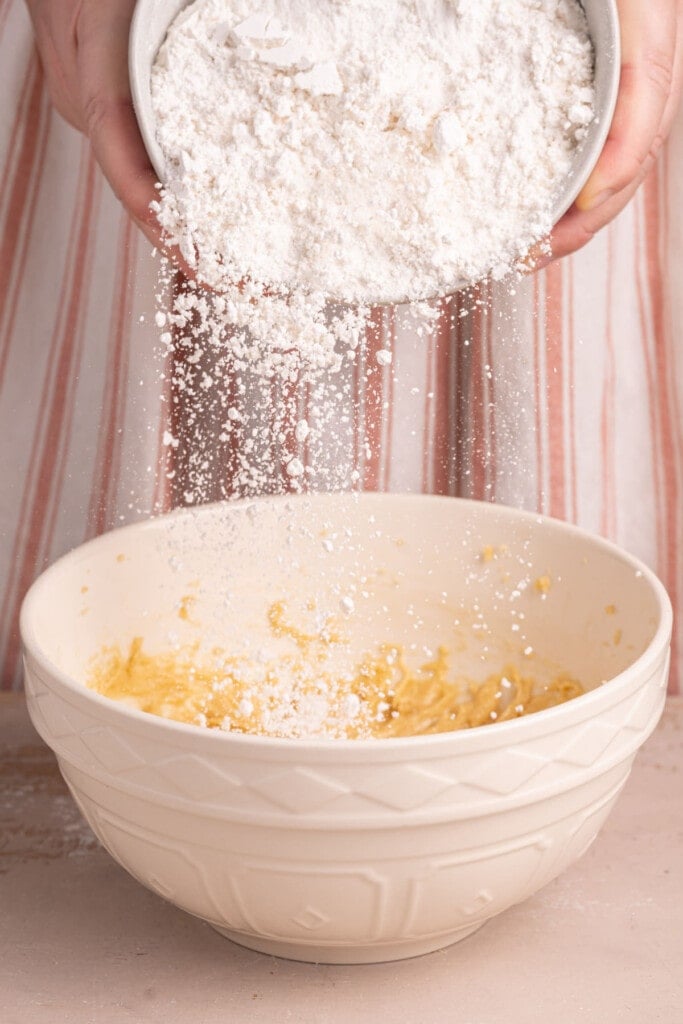 Adding flour to chocolate chip cookie dough with pecans and caramel.