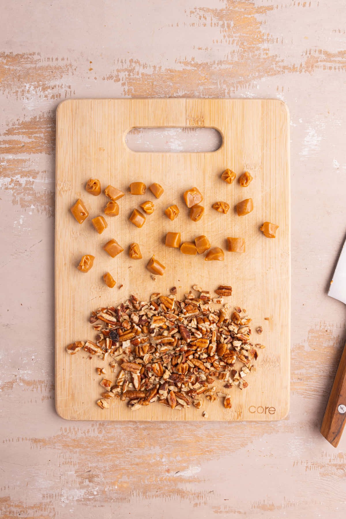 Chopping board with prepped chewy caramel and chopped pecans