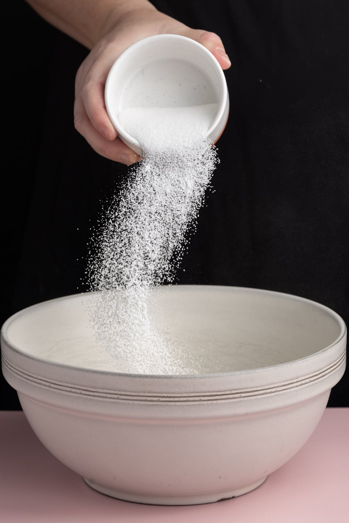 Adding granulated sugar to a mixing bowl with softened butter and brown sugar to cream together