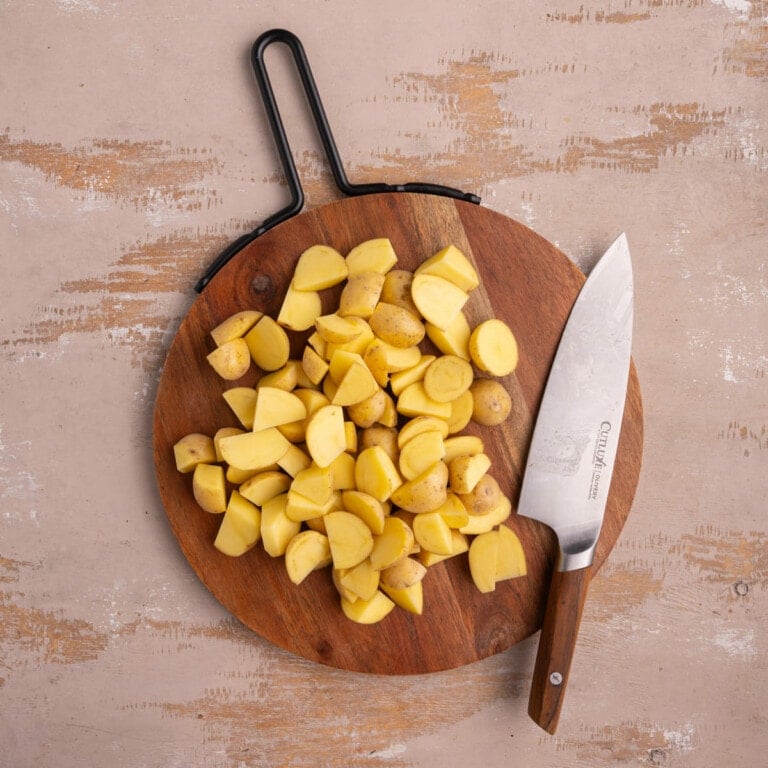 Honey gold potatoes chopped into wedges on a cutting board