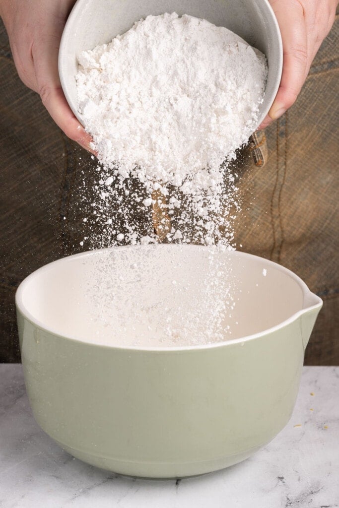 Adding flour to mixing bowl to make lemon pancakes.
