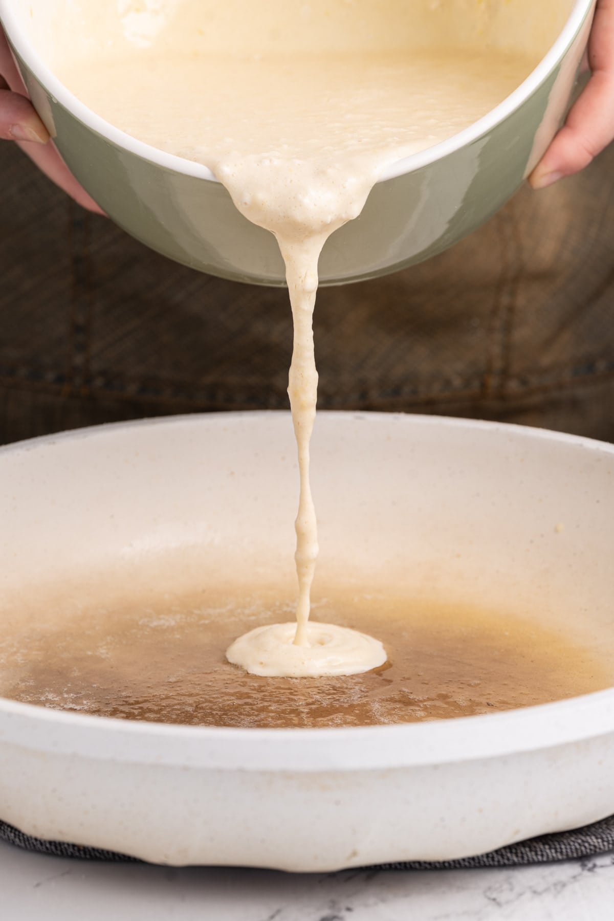 Pouring pancake batter into frying pan with hot butter