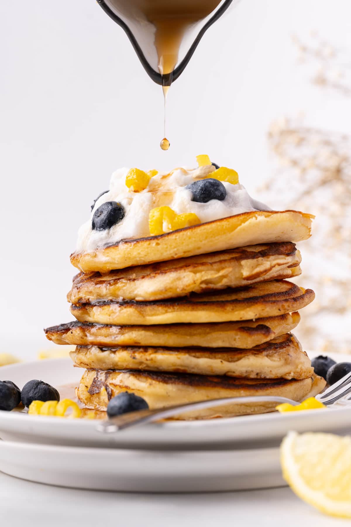 Maple syrup dripping onto stack of lemon pancakes