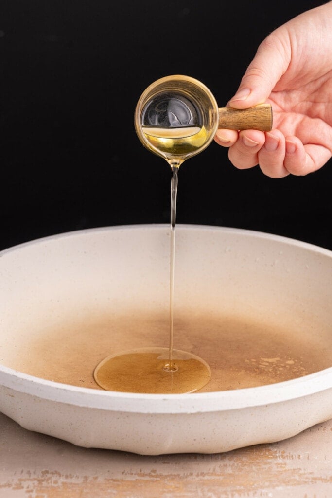 Adding olive oil to frying pan to get hot before adding potatoes and onions.