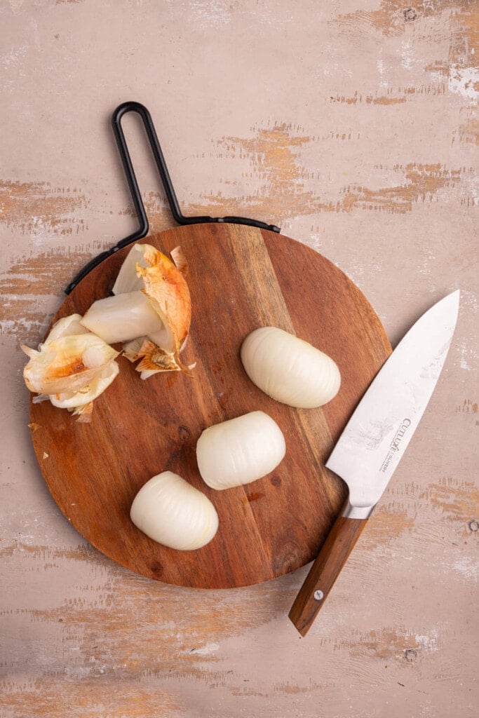 Peeling outer layer off of onion and laying flat on shopping board to easily slice