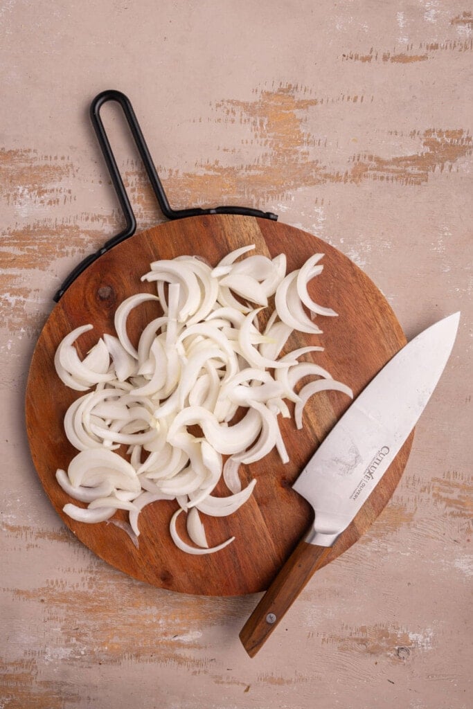 Onions sliced thin on a chopping board.