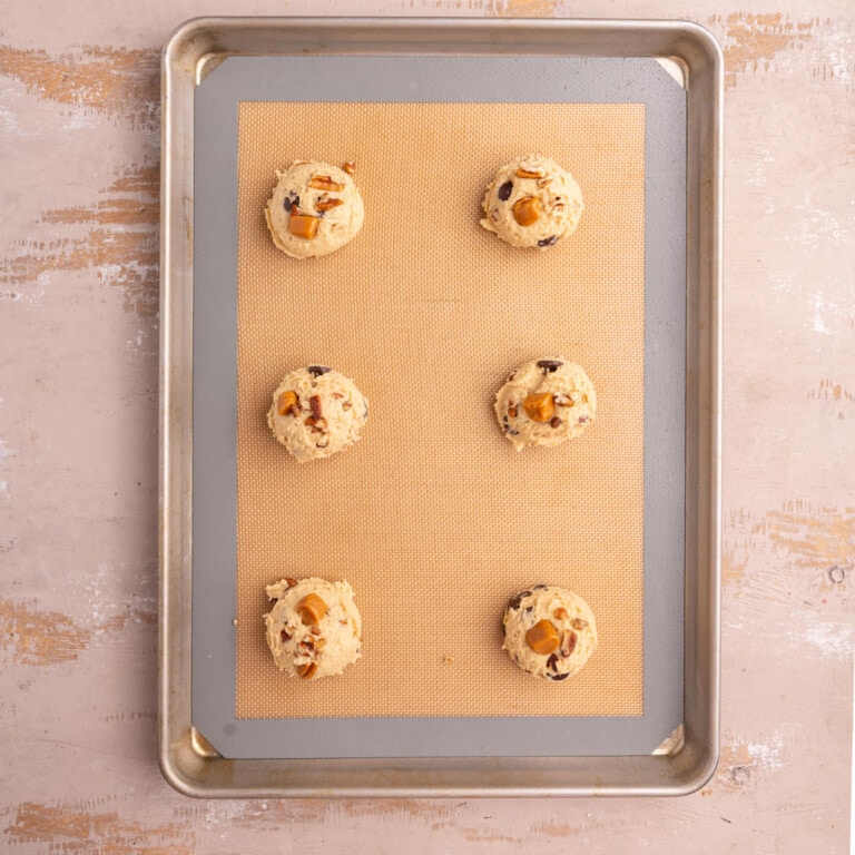 Lined baking sheet with shaped turtle cookie dough