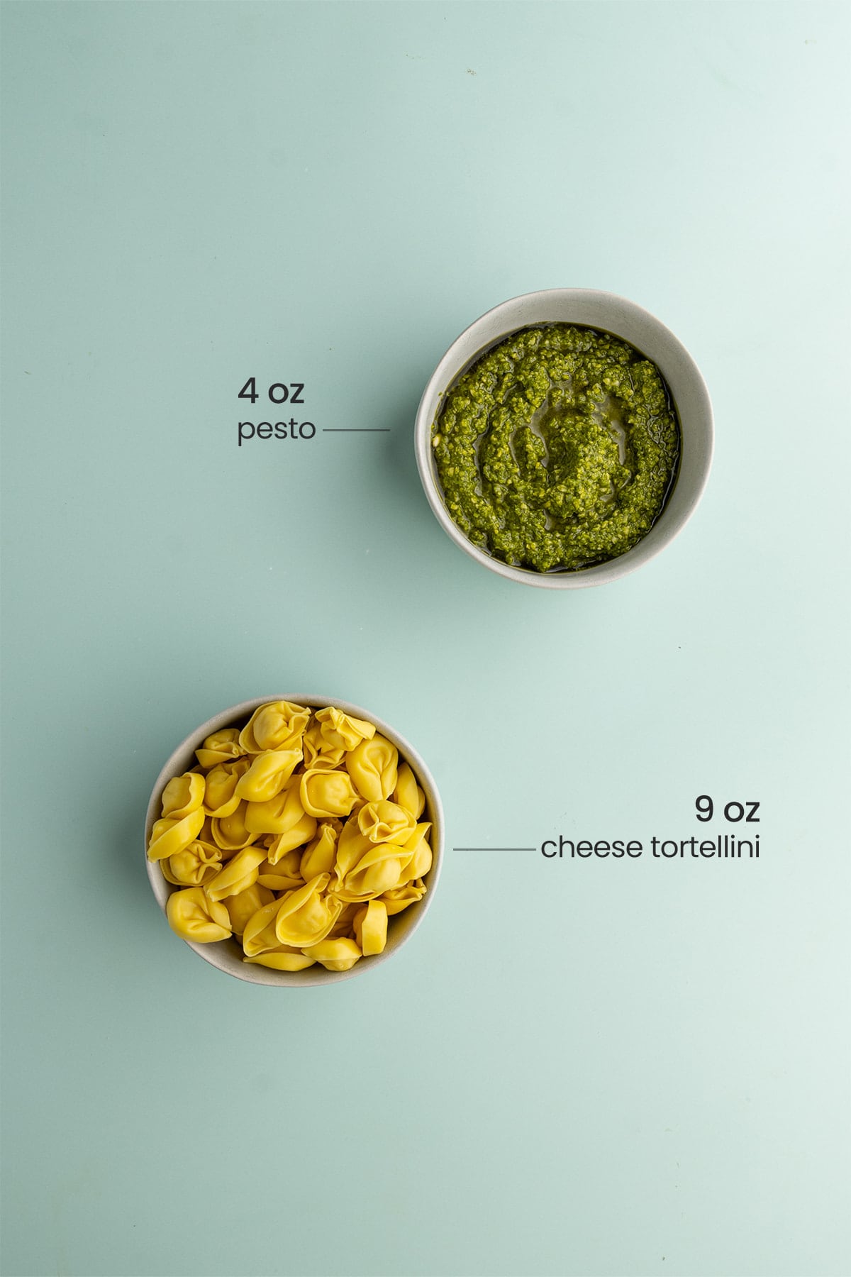 a bowl of uncooked cheese tortellini and a bowl of pesto