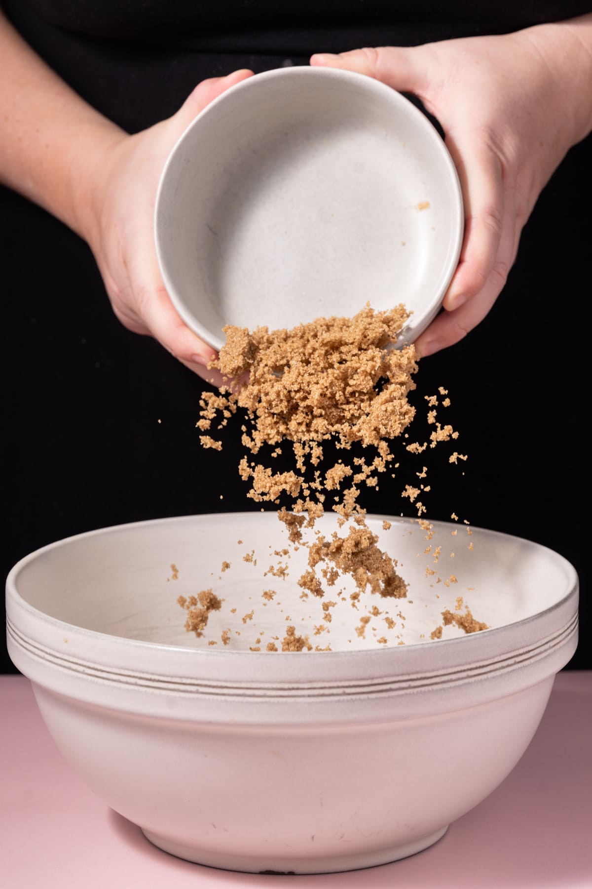 Adding dark brown sugar to a mixing bowl to cream with butter