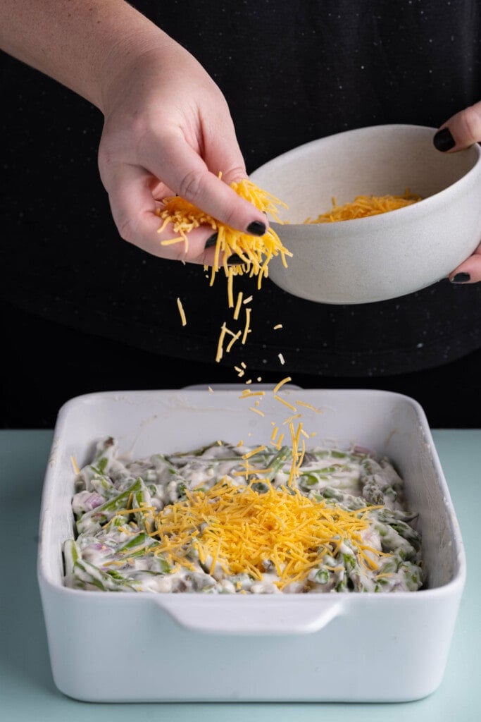 Adding shredded cheddar cheese to asparagus casserole