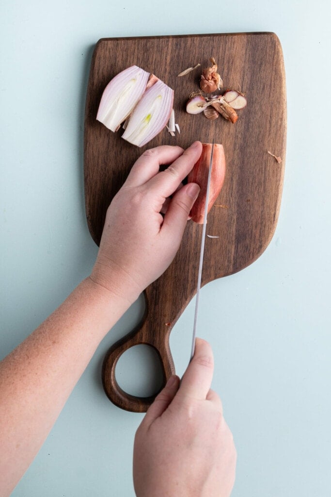 Slicing a shallot in half so its easier to peel