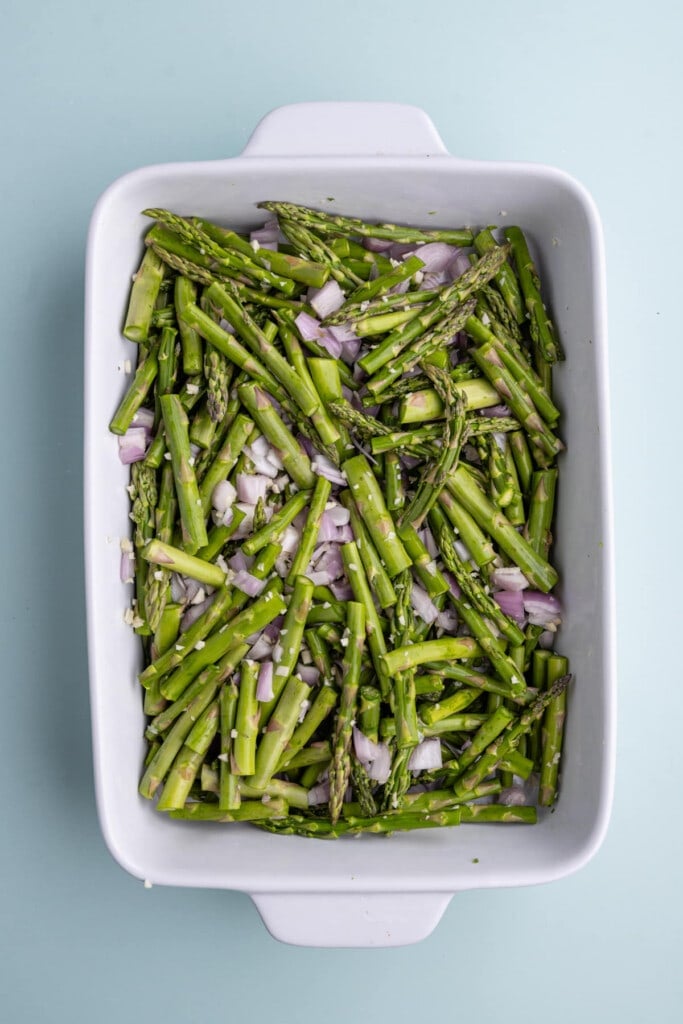 Mixing asparagus, shallots, and garlic in a casserole dish