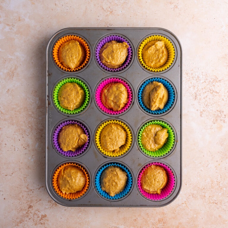 Large muffin tin lined with reusable liners filled with banana pumpkin batter