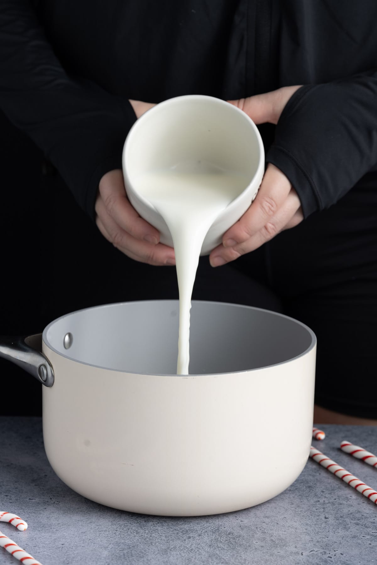 Pouring milk into a small pot to heat with chocolate chips