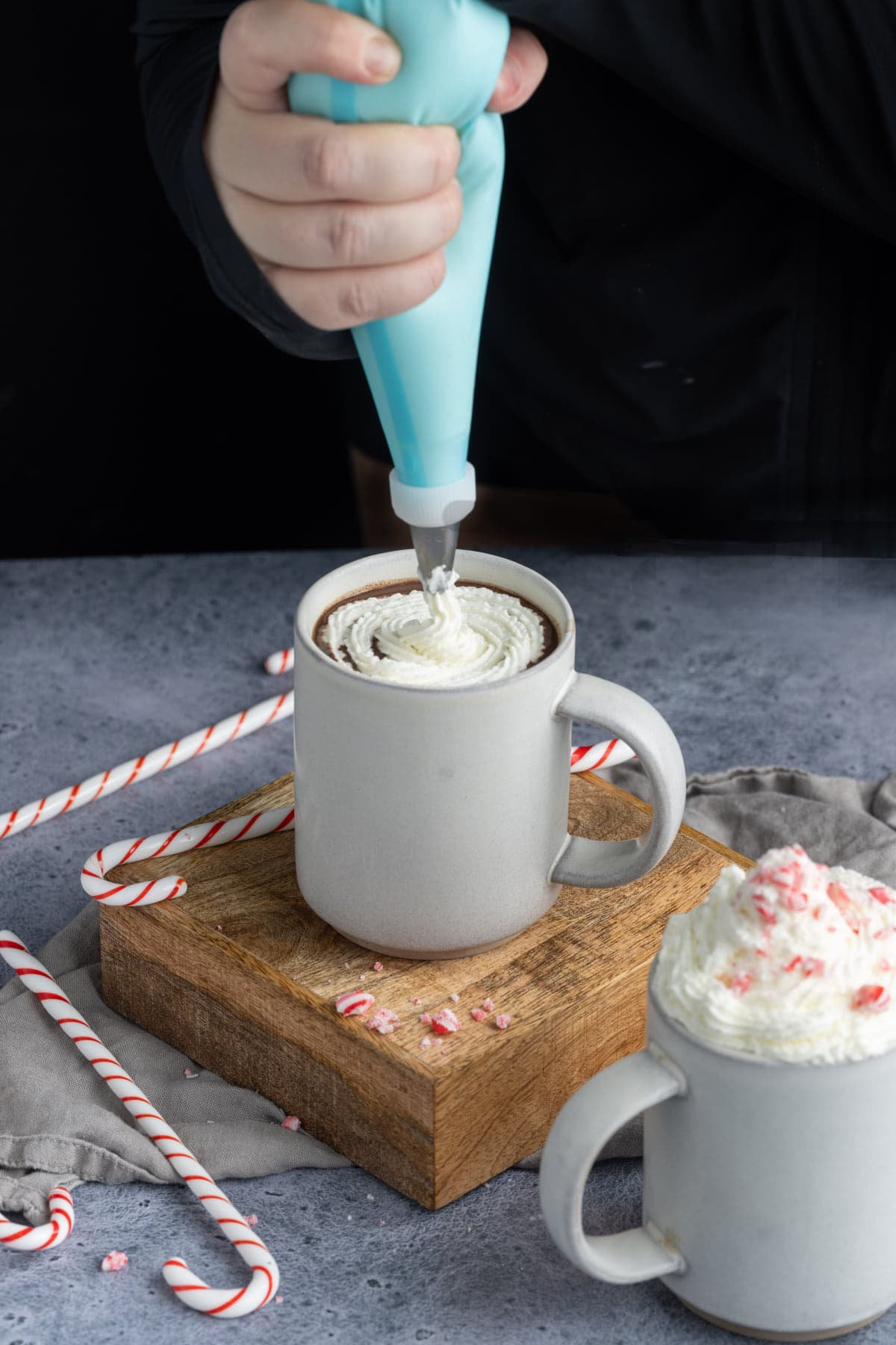 Adding whipped cream to mug of peppermint hot chocolate