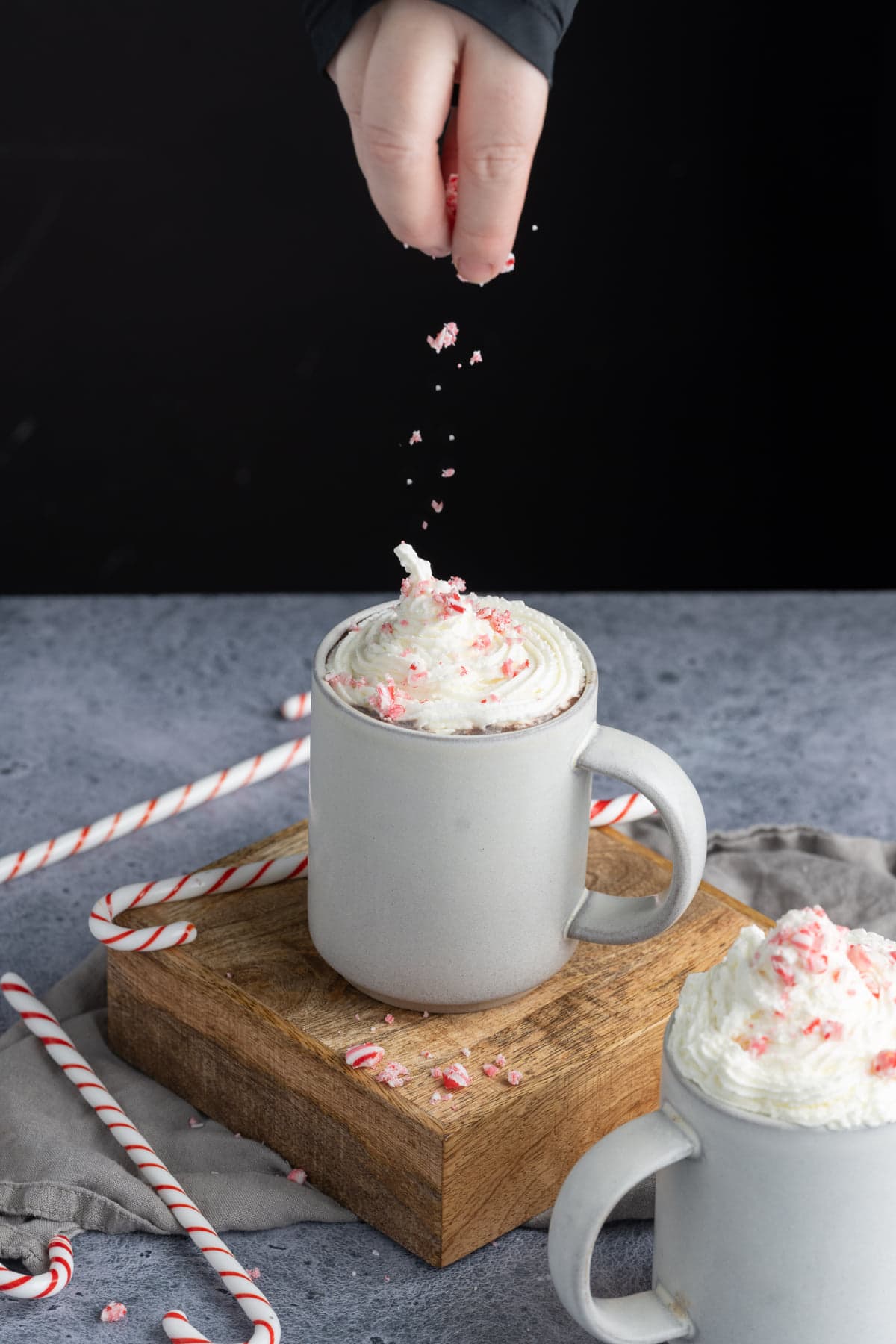 Adding crushed candy cane on top of whipped cream and hot cocoa