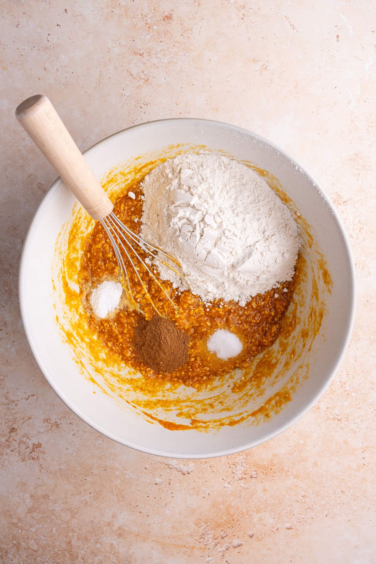 Adding flour, baking soda, salt, and pumpkin pie spice to banana pumpkin muffin batter