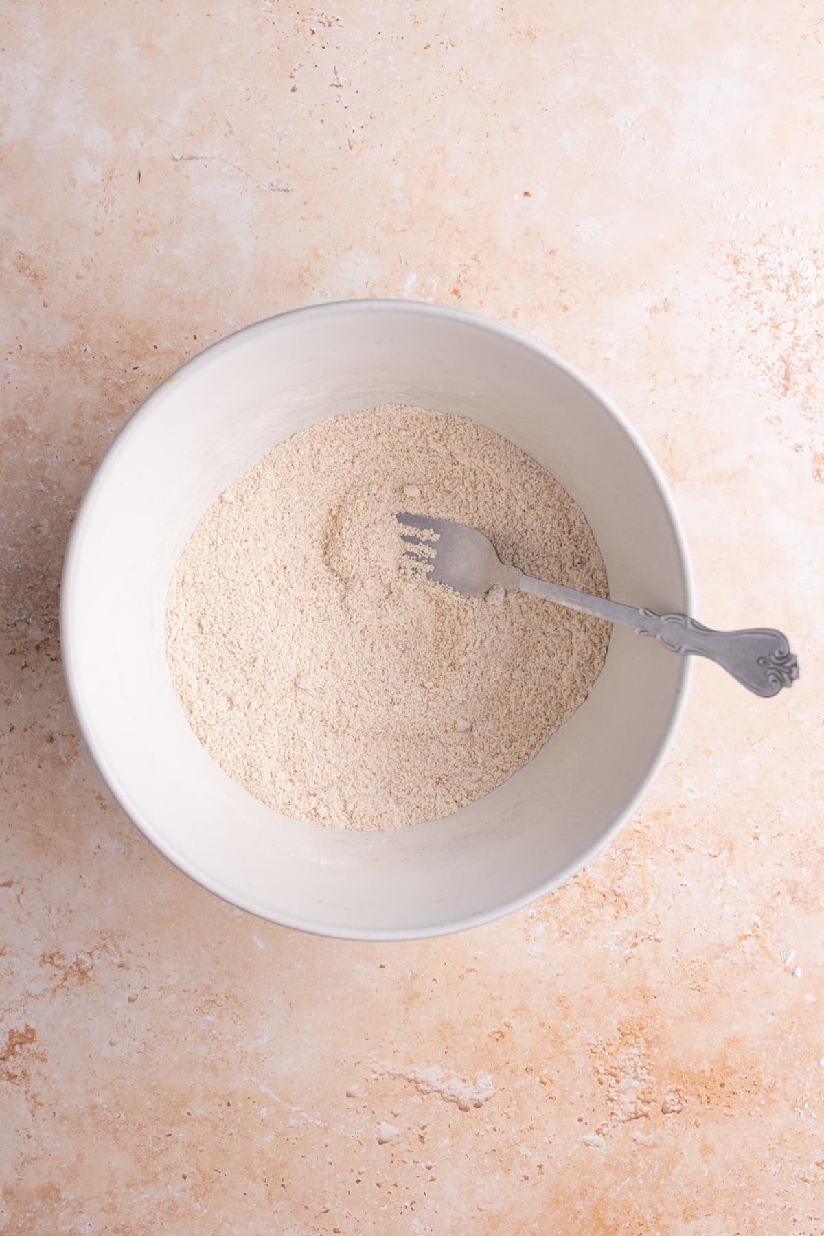 Using a fork to combine flour, brown sugar, and pumpkin pie spice