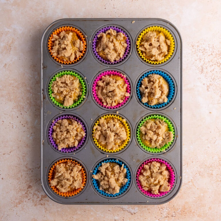 Muffin tin filled with banana pumpkin batter and crumble top
