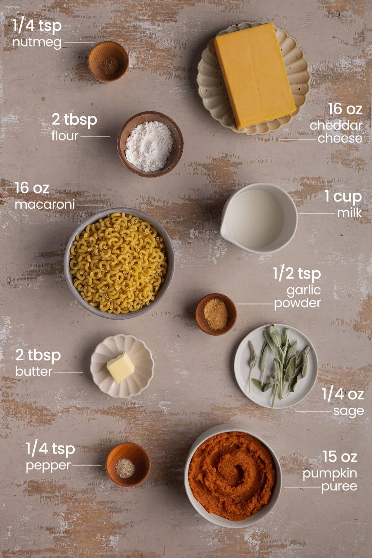 ingredients for pumpkin mac and cheese - nutmeg, flour, cheddar cheese, macaroni, milk, garlic powder, butter, sage, pumpkin puree, pepper