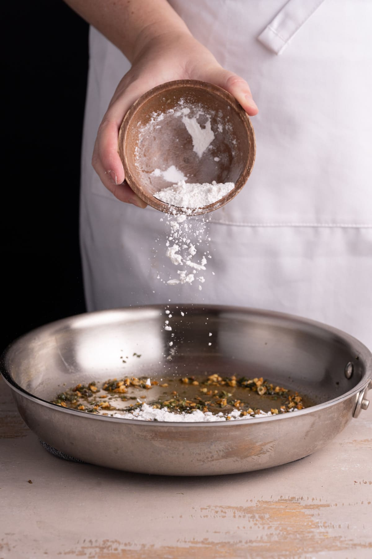 Adding flour to form a roux for a creamy sauce