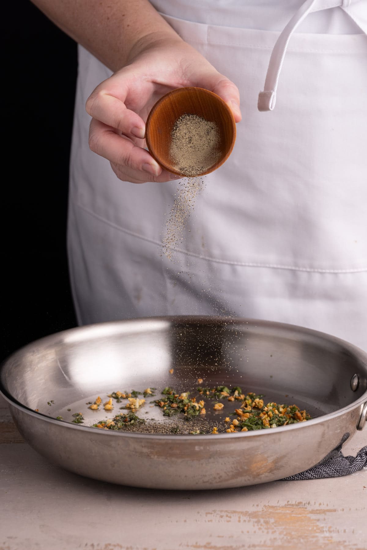 Adding pepper to creamy coconut sage sauce