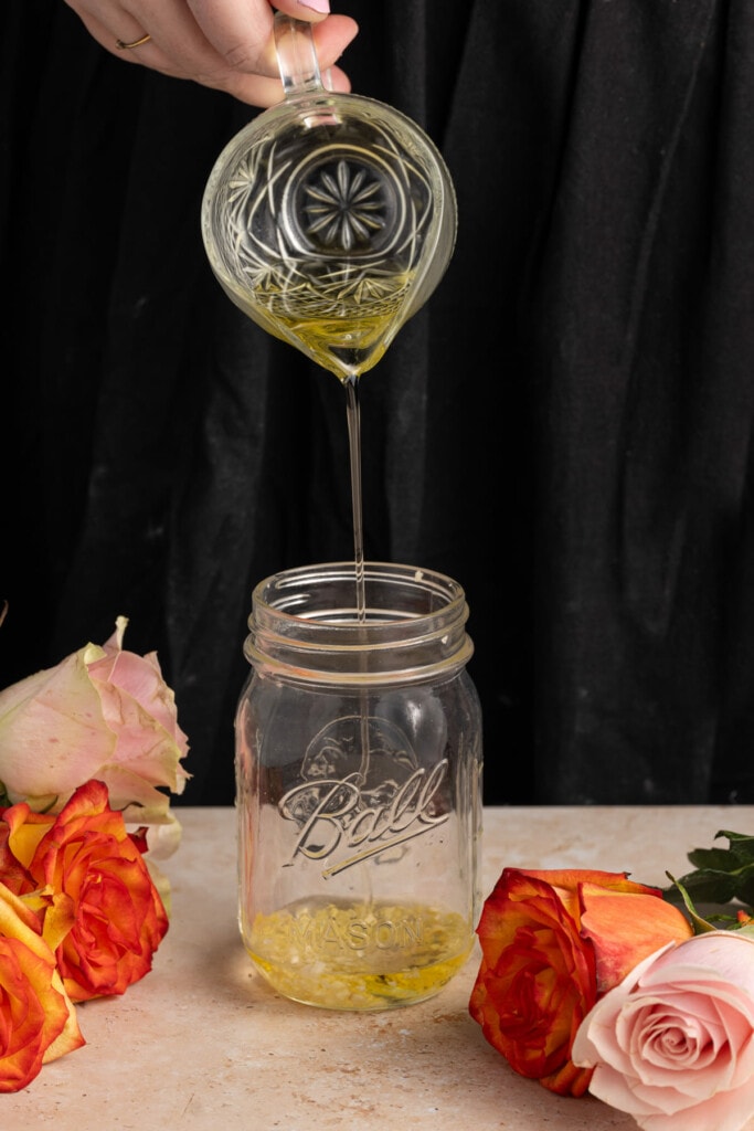 Adding olive oil to a mason jar with garlic 