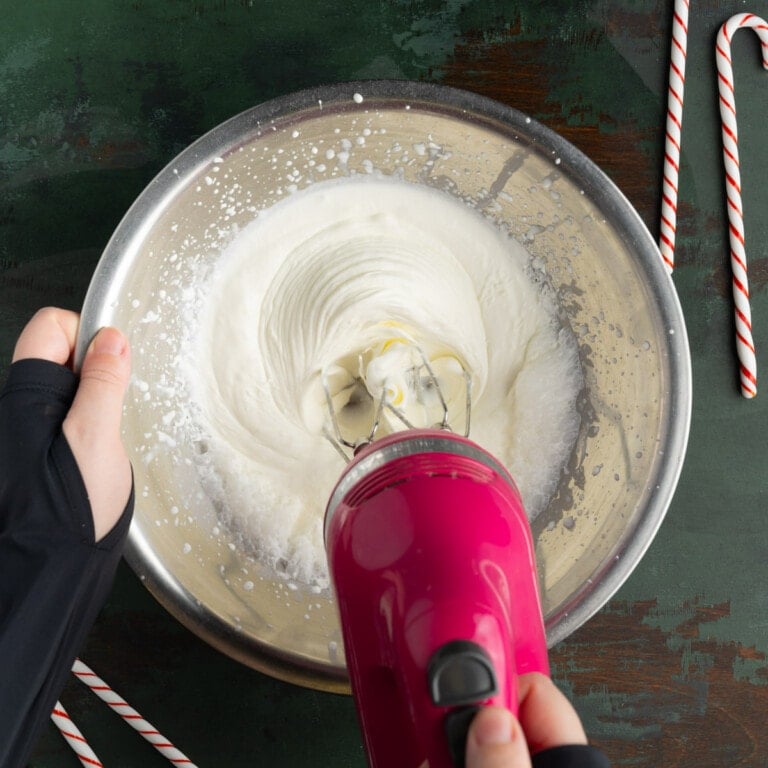 Whipping heavy cream with a hand mixer until stiff peaks form