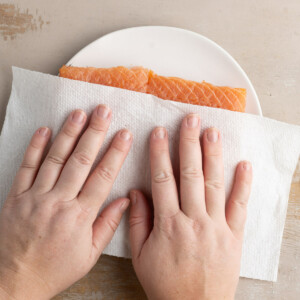 Blotting salmon dry with a paper towel
