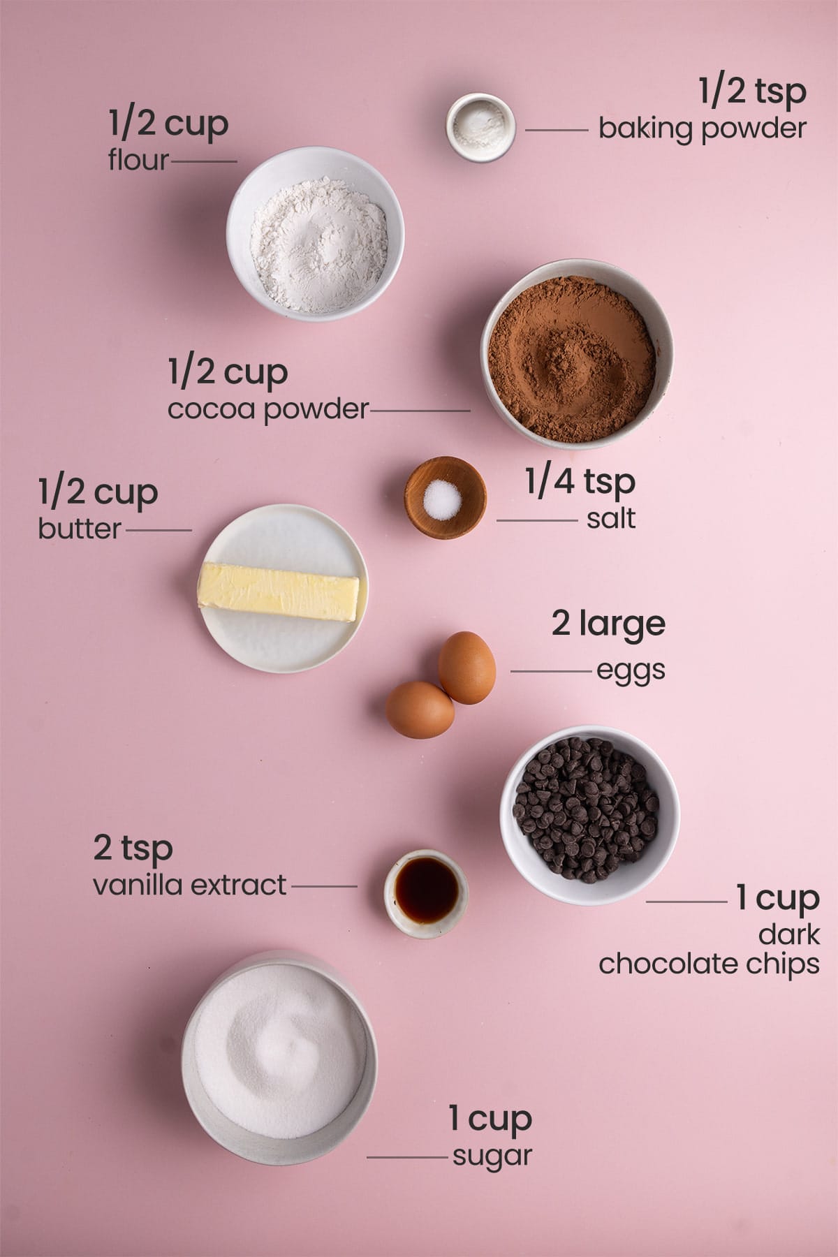 All ingredients needed for brownie bites including baking powder, sugar, butter, cocoa powder, salt, eggs, chocolate chips, vanilla extract, and flour