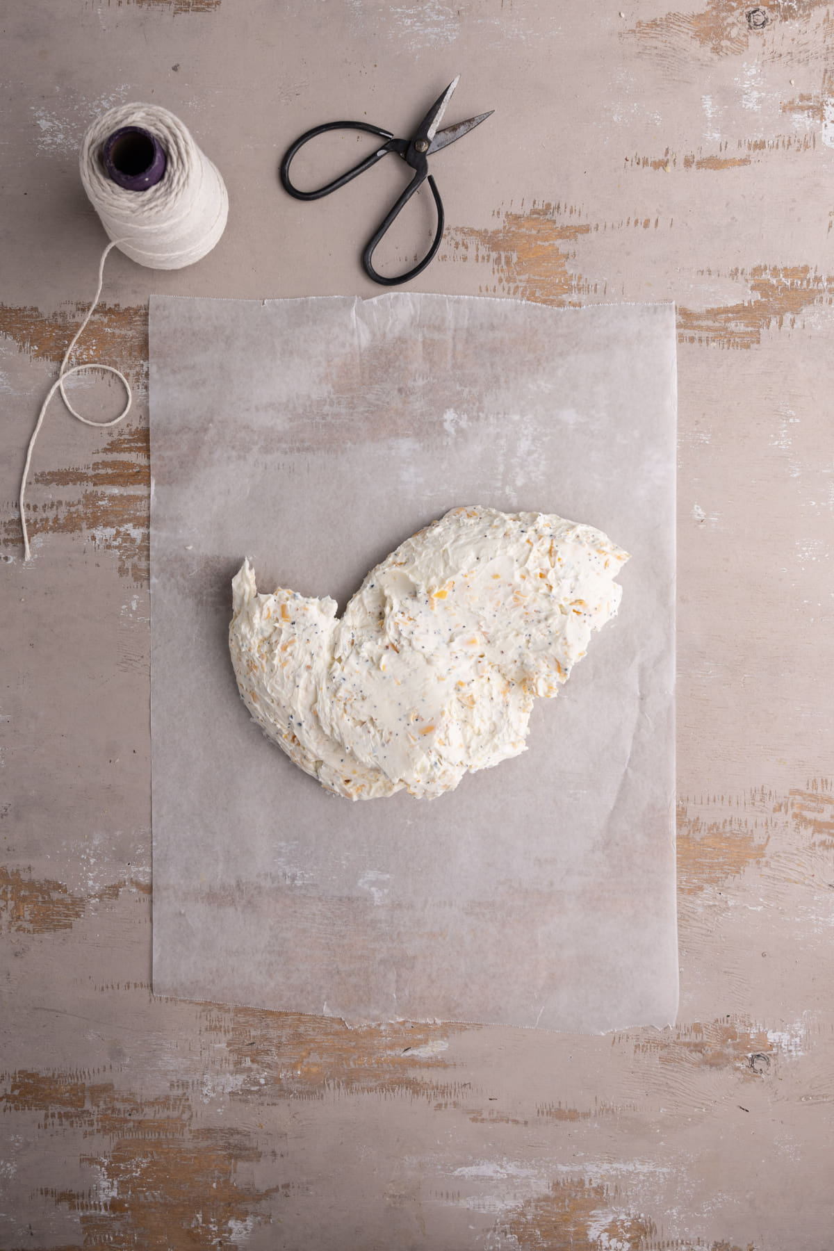 Turning seasoned cream cheese out onto wax paper to shape it into a ball. 