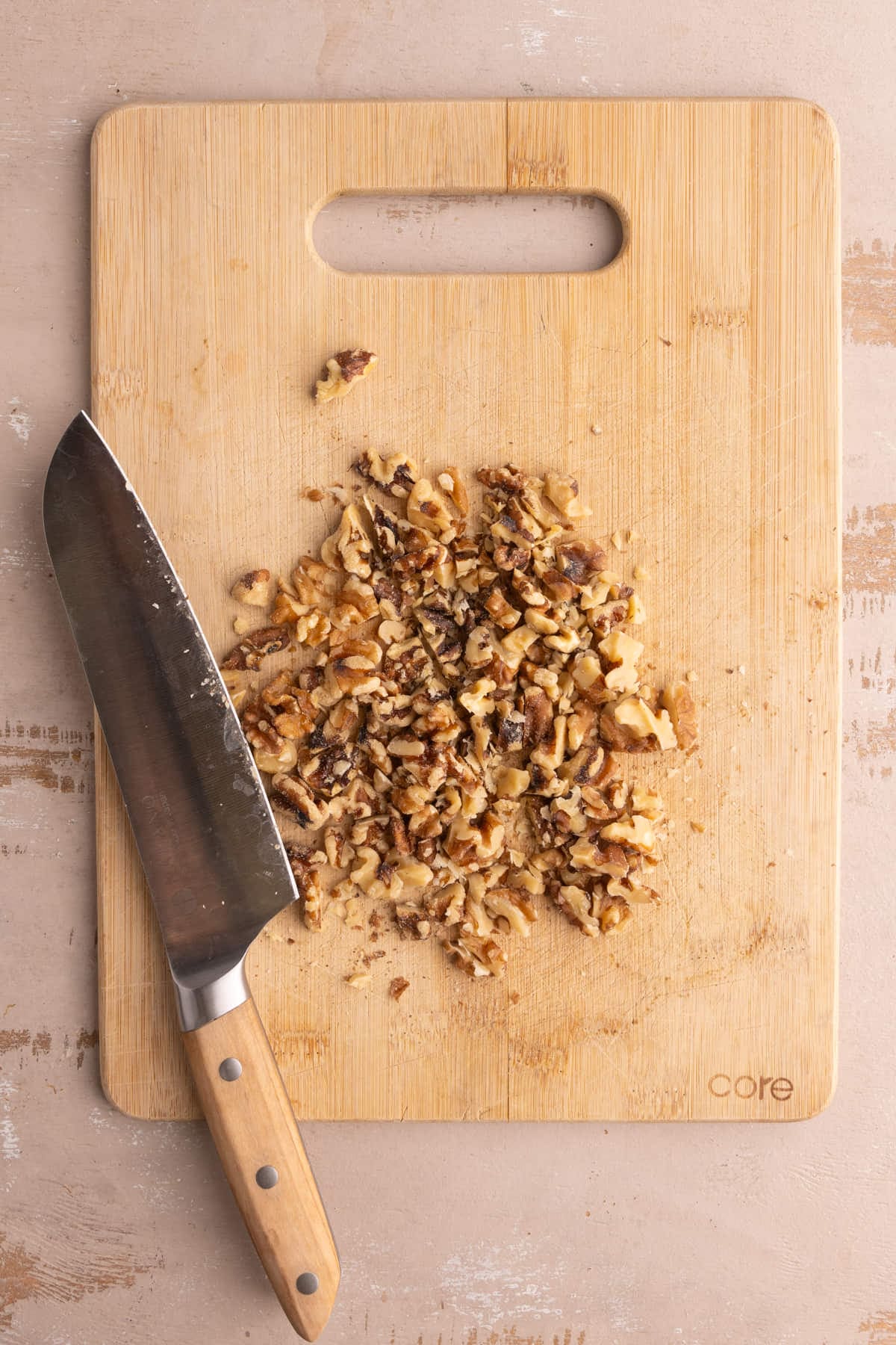 Cutting board piled with chopped walnuts to add to chocolate chip cookies.