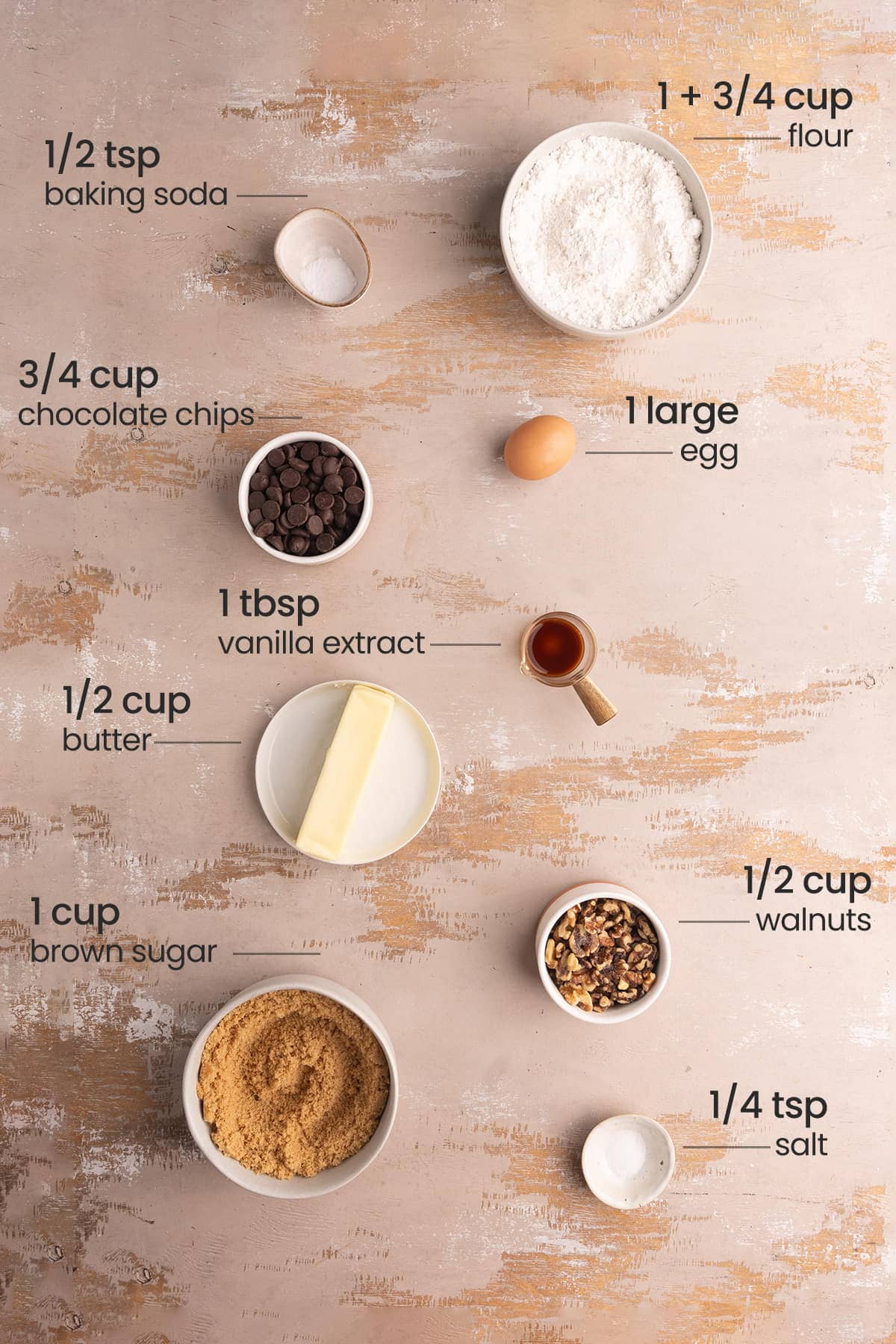 All ingredients needed for Chocolate Chip Walnut Cookies including flour, baking soda, egg, chocolate chips, vanilla extract, butter, walnut, brown sugar, and salt