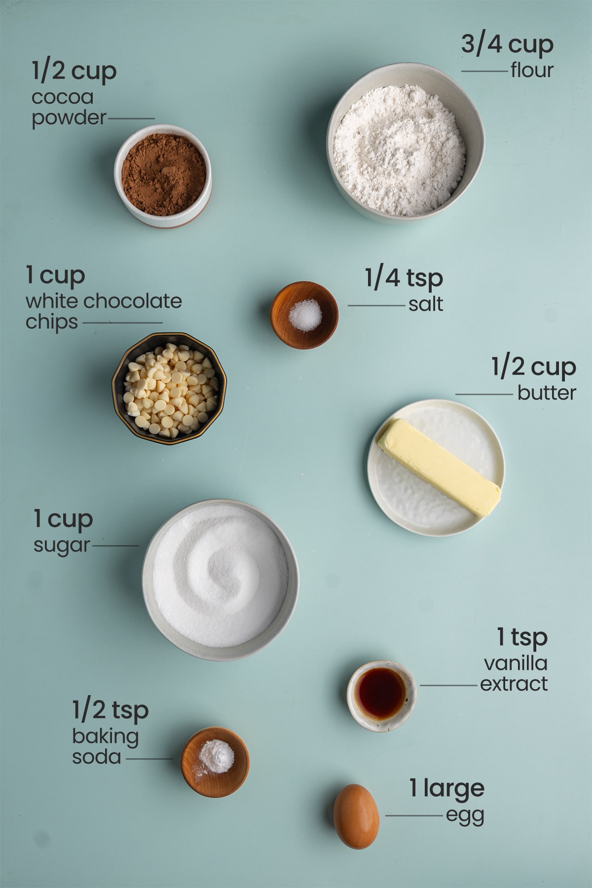 All ingredients needed for Chocolate Cookies with White Chocolate Chips including cocoa powder, flour, salt, white chocolate chips, unsalted butter, granulated sugar, vanilla extract, baking soda, and an egg