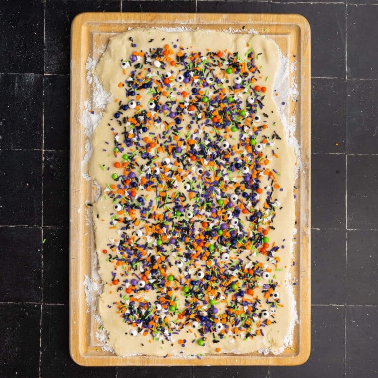 Sugar cookie dough rolled out and topped with Halloween themed sprinkles.