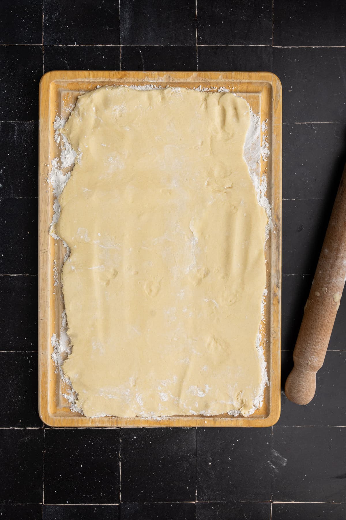 Rolling sugar cookie dough out on a floured surface to use cookie cutters.